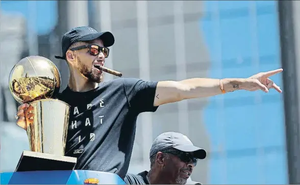  ?? MARCIO JOSÉ SÁNCHEZ / AP ?? Stephen Curry se fuma un cigarro mientras sostiene el trofeo de campeón de la NBA, el pasado 15 de junio