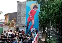  ?? AP ?? People stand beside statue of Diego Maradona during its presentati­on in Buenos Aires. —