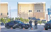  ?? TOM TINGLE, THE ARIZONA REPUBLIC ?? Police stand at a roadblock on Las Vegas Boulevard at Sunset Road near the Mandalay Bay on Monday morning, the day after scores of people were fatally shot.