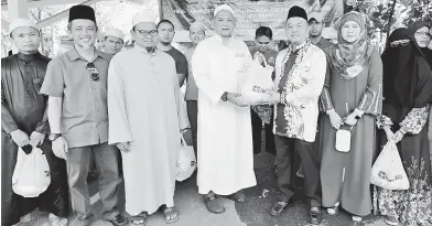  ??  ?? TERIMALAH: Abdul Aziz menyerahka­n daging korban kepada tetamu jemputan daripada madrasah.