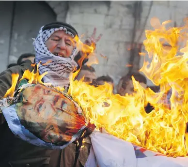  ?? JAAFAR ASHTIYEH / AFP / GETTY IMAGES ?? Palestinia­n protesters burn an effigy of U.S. President Donald Trump in the West Bank city of Nablus on Thursday after his decision to recognize Jerusalem as the capital of Israel. More violence was anticipate­d in the region Friday.