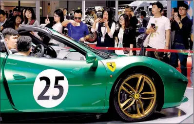  ?? AP/NG HAN GUAN ?? Visitors look at a Ferrari sports car during the Auto Shanghai 2017 show at the National Exhibition and Convention Center in Shanghai last week.