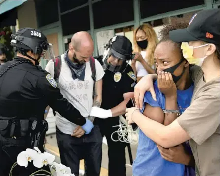  ?? Wally Skalij Los Angeles Times ?? PROTESTERS EMBRACE as another is led away in handcuffs by police on Sunday in Santa Monica amid the COVID-19 pandemic.