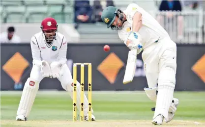  ??  ?? MELBOURNE: Australian batsman Joe Burns (R) lofts the ball away to the boundary as West Indies wicketkeep­er Denesh Ramdin (L) looks on, on the first day of the second cricket Test in Melbourne yesterday. — AFP
