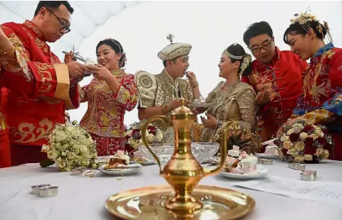  ??  ?? Sweet union: Couples feeding one another during the mass wedding ceremony in Colombo.