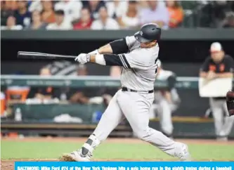  ?? — AFP ?? BALTIMORE: Mike Ford #74 of the New York Yankees hits a solo home run in the eighth inning during a baseball game against the Baltimore Orioles at Oriole Park at Camden Yards in Baltimore, Maryland.