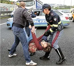  ?? /Reuters ?? Police officers remove a man as Italian climate activists block a highway in Rome on Wednesday. African activists demonstrat­ed at the COP27 meeting in Egypt in favour of compensati­on from rich countries to poor countries affected by climate change.