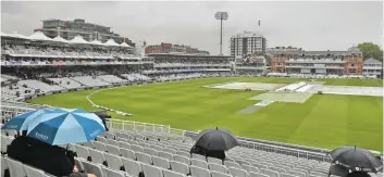  ??  ?? Fans take shelter under umbrellas as rain delays the start of play on the first day of the second Test at Lord’s. —AP