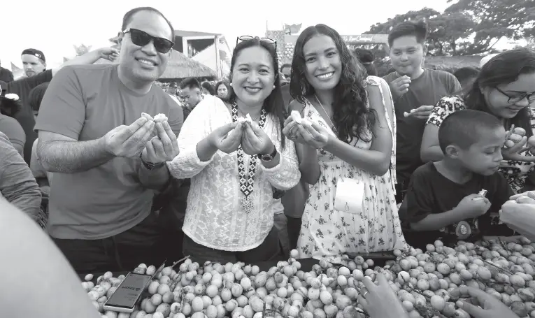  ?? Joey O. Razon) (PNA photo by ?? EAT ALL YOU CAN. Department of Tourism (DOT) Region 10 Director Marie Elaine Unchua (middle) leads the eat all you can of lanzones during the celebratio­n of the 40th Lanzones Festival in Mambajao, Camiguin on Saturday (Oct. 26, 2019). Camiguin is known for its abundant harvest of sweet lanzones that begins every third week of October.