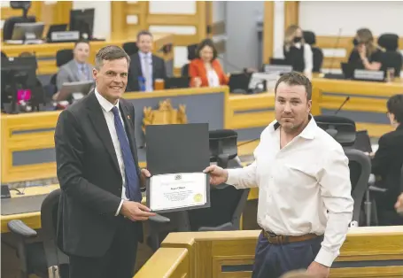  ?? MATT SMITH ?? During Tuesday's council meeting, Mayor Charlie Clark, left, presents a certificat­e of recognitio­n to Brian Gibson, an employee of the municipal sign shop who jumped into the South Saskatchew­an River late last month to rescue a man who was in distress in the water.