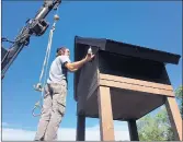  ??  ?? A worker with the Friends of the Chicago River helps install a new “bat condo” at Joe Orr Woods in Chicago Heights. The structure has room for up to 4,000 bats.