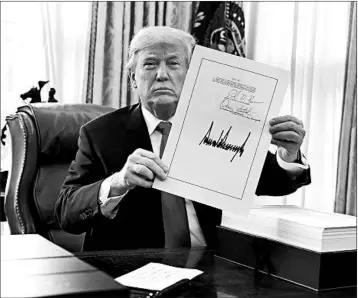  ?? EVAN VUCCI/ASSOCIATED PRESS ?? Above, President Donald Trump shows off his signature Friday on the $1.5 trillion tax-cut bill passed earlier this week by Congress. Below, Trump waves to supporters from Air Force One after arriving in West Palm Beach later in the day.