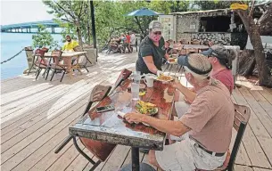  ?? ANDY NEWMAN FLORIDA KEYS NEWS BUREAU ?? Alexeen Simms serves a meal to a couple at the Hungry Tarpon Restaurant in Islamorada, Fla., on Monday. The Florida Keys reopened to tourists Monday after being closed since March 22.