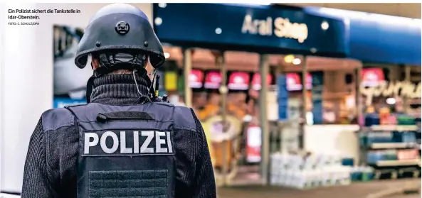  ?? FOTO: C. SCHULZ/DPA ?? Ein Polizist sichert die Tankstelle in Idar-oberstein.