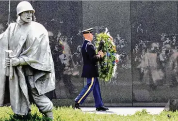  ?? Rick Bowmer / Associated Press ?? A wreath-bearer makes his way past the wall of the Korean War Memorial at the National Mall in Washington. The statue of the infantryma­n at left is part of the memorial.