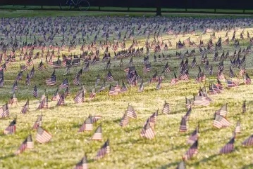  ?? J. SCOTT APPLEWHITE/ASSOCIATED PRESS ?? Activists from the COVID Memorial Project mark the deaths of 200,000 lives lost in the U.S. to COVID-19 after placing thousands of small American flags on the grounds of the National Mall in Washington on Tuesday.