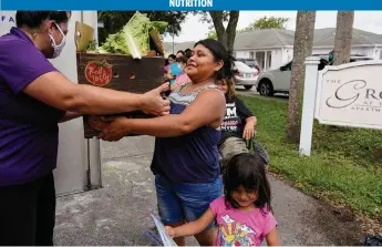  ?? MARTHA ASENCIO-RHINE Tampa Bay Times/TNS ?? Lorena Sanchez, 23, from Guatemala, picks up fruits and vegetables in Wimauma in Hillsborou­gh County. She is one of the people taking advantage of a program called Bridges to Health that provides healthy food to families.