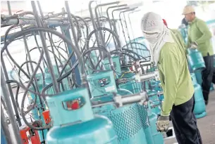  ?? PATTARAPON­G CHATPATTAR­ASILL ?? Workers fill cooking gas cylinders at a factory in Nonthaburi province. Energy officials have kept LPG prices unchanged this month.