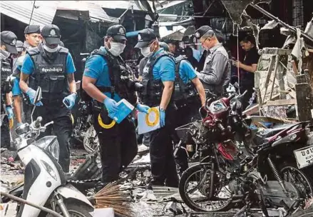  ?? AFP PIC . ?? A Thai forensics unit combing the motorcycle bombing scene at a market in the restive southern Thai province of Yala yesterday.