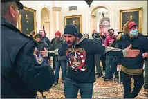  ?? MANUEL BALCE CENETA / AP ?? Trump supporters gesture to U.S. Capitol Police in the hallway outside of the Senate chamber Jan. 6 at the Capitol in Washington, D.C.