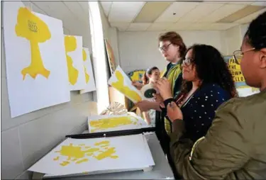  ?? TANIA BARRICKLO — DAILY FREEMAN ?? Kingston High School students hang up silkscreen posters to dry during Open Studio at the YMCA in Kingston. From right are Briana Gary, 16, Chloe Redd, 16, Gregory Haller, 16, and Alexis Kain, 15.