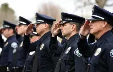  ?? ?? Local law enforcemen­t officers stand in formation the ceremony. Talley’s patrol car, which has been parked outside of the department since Friday, was covered with flowers, messages and other mementos to honor the fallen officer.