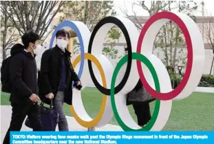 ??  ?? TOKYO: Visitors wearing face masks walk past the Olympic Rings monument in front of the Japan Olympic Committee headquarte­rs near the new National Stadium.