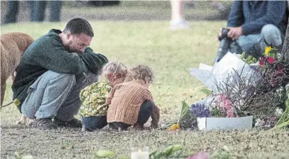  ?? MARTY MELVILLE AFP/GETTY IMAGES ?? A father and his children honour victims with floral tributes across the road from the Masjid Al Noor mosque in Christchur­ch, New Zealand, where worshipper­s were gunned down three days ago.