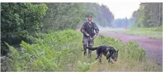  ?? FOTO: MINDAUGAS KULBIS/DPA ?? Ein Mitglied des litauische­n Grenzschut­zes patrouilli­ert im Juni mit einem Hund an der Grenze zu Belarus.