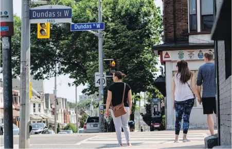  ??  ?? Pedestrian­s wait to cross an intersecti­on on Dundas Street West in Toronto on Wednesday. The street was named after Henry Dundas, an 18th-century politician who delayed Britain's abolition of slavery by 15 years.