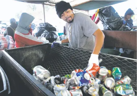  ?? Paul Chinn / The Chronicle ?? Ed Rodriguez slides cans onto a scale to weigh for a customer at the Our Planet Recycling collection center in the Bayview.