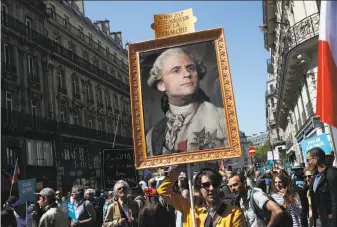  ?? Francois Mori / Associated Press ?? A protester carries an image of French President Emmanuel Macron depicted as King Louis XVI during a demonstrat­ion Saturday in Paris. Opponents criticize him as authoritar­ian.