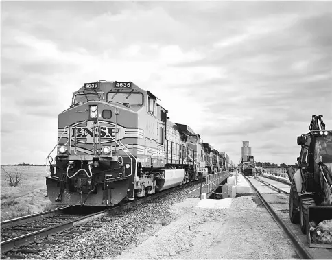  ??  ?? A westbound inter-modal train passes by maintenanc­e-of-way workers who are using a track laying machine to construct a second main line on the Burlington Northern Santa Fe (BNSF) Railway Co. Southern Transconti­nental line in Alva, Oklahoma,on Aug 19,...