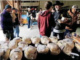  ?? ARCHIVES] [PHOTO BY JIM BECKEL, THE OKLAHOMAN ?? A man, holding a box of doughnuts, thanks a volunteer as he receives his frozen turkey in the Jesus House distributi­on warehouse last year.