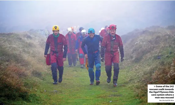  ?? Ben Birchall/PA Wire ?? > Some of the 242 rescuers walk towards the Ogof Ffynnon Ddu cave system where a
man was rescued