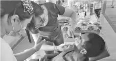  ??  ?? A dentist checking the teeth of a villager during the health and medical camp.