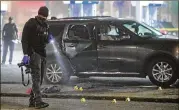  ?? JOHN SPINK/JOHN.SPINK@AJC.COM ?? An all too familiar scene in the city: A police investigat­or scours the scene of a street shooting, this one outside a gas station in southwest Atlanta, that erupted late at night and resulted in two men inside an SUV being seriously wounded.