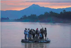  ?? MARCO UGARTE/ASSOCIATED PRESS ?? Central American migrants stand on a raft to cross from Guatemala to Mexico, with the Tacana volcano in the background, near Ciudad Hidalgo, Mexico, in June.