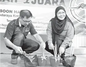  ??  ?? NOORLIZA (kanan) dan Koay menyempurn­akan gimik penanaman serai wangi yang mampu menghalau nyamuk aedes.