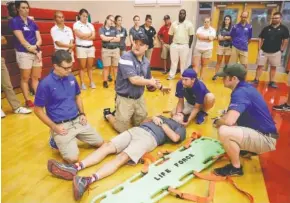  ?? STAFF PHOTOS BY DOUG STRICKLAND ?? Paramedic Kevin Gebicke, with Erlanger Lifeforce’s Event Medicine crew, center, explains how to move a patient onto a backboard Friday during a backboard-immobiliza­tion workshop hosted by Erlanger hospital at Signal Mountain Middle High School.