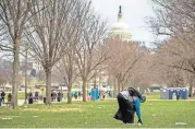  ?? [AP PHOTO] ?? The Capitol building is visible as a man picks up garbage Tuesday in Washington.
