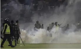  ?? Photograph: Yudha Prabowo/AP ?? Police and soldiers on the stadium’s pitch after teargas was fired.