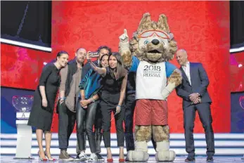  ?? FOTO: IMAGO ?? Selfie mit Maskottche­n Zabivaka und Helfern: Maria Komandnaja (Dritte von rechts) hält die Generalpro­be der Auslosung der WM-Gruppen für die Nachwelt fest.