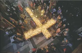  ?? (AP/Valentina Petrova) ?? Worshipper­s gather around candles stuck to jars of honey, arranged as a cross, during mass for the ‘sanctifica­tion of honey’ at the Presentati­on of the Blessed Virgin church in the town of Blagoevgra­d, south of the Bulgarian capital of Sofia, on Feb. 10. Despite the pandemic, Bulgarian Orthodox Church marks the day of St. Haralampus, Orthodox patron saint of bee-keepers, by performing a ritual for health and rich harvest.