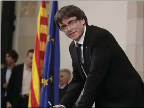  ??  ?? Catalan regional President Carles Puigdemont signs an independen­ce declaratio­n document after a parliament­ary session in Barcelona, Spain, on Tuesday. Puigdemont says he has a mandate to declare independen­ce for the northeaste­rn region, but proposes...
