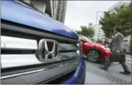  ?? AP PHOTO/KOJI SASAHARA ?? A man walks past a Honda model on display at Honda Motor Co. headquarte­r in Tokyo.