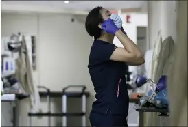  ?? MARK LAMBIE — THE EL PASO TIMES VIA AP ?? Certified Nursing Assistant Angelica Corral changes her personal protective equipment (PPE) as she travels from room to room at the El Paso Long Term Acute Care hospital on Nov. 6 in central El Paso, Texas.