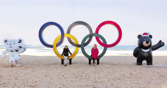  ?? Foto: AP ?? S kruhy a maskoty Na pláži v Kangnungu už se lidé fotí s olympijský­mi symboly. Bílý tygr Soohorang je maskotem blížící se olympiády, černý medvěd Bandabi paralympiá­dy.