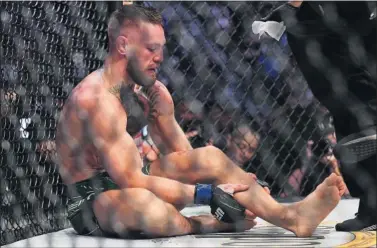  ??  ?? Conor McGregor espera asistencia médica tras fracturars­e la tibia en su combate ante Poirier.