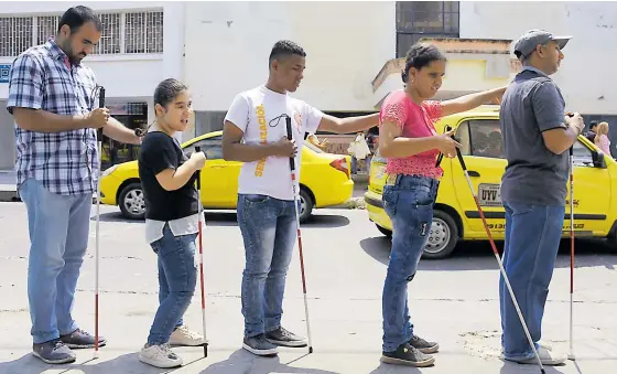  ?? FOTOS JOSEFINA VILLARREAL ?? Esta es la fila que forman los jóvenes con discapacid­ad visual, mientras hacen el recorrido por la calle 41 para llegar a la carrera 41, en el Centro, donde está el restaurant­e.